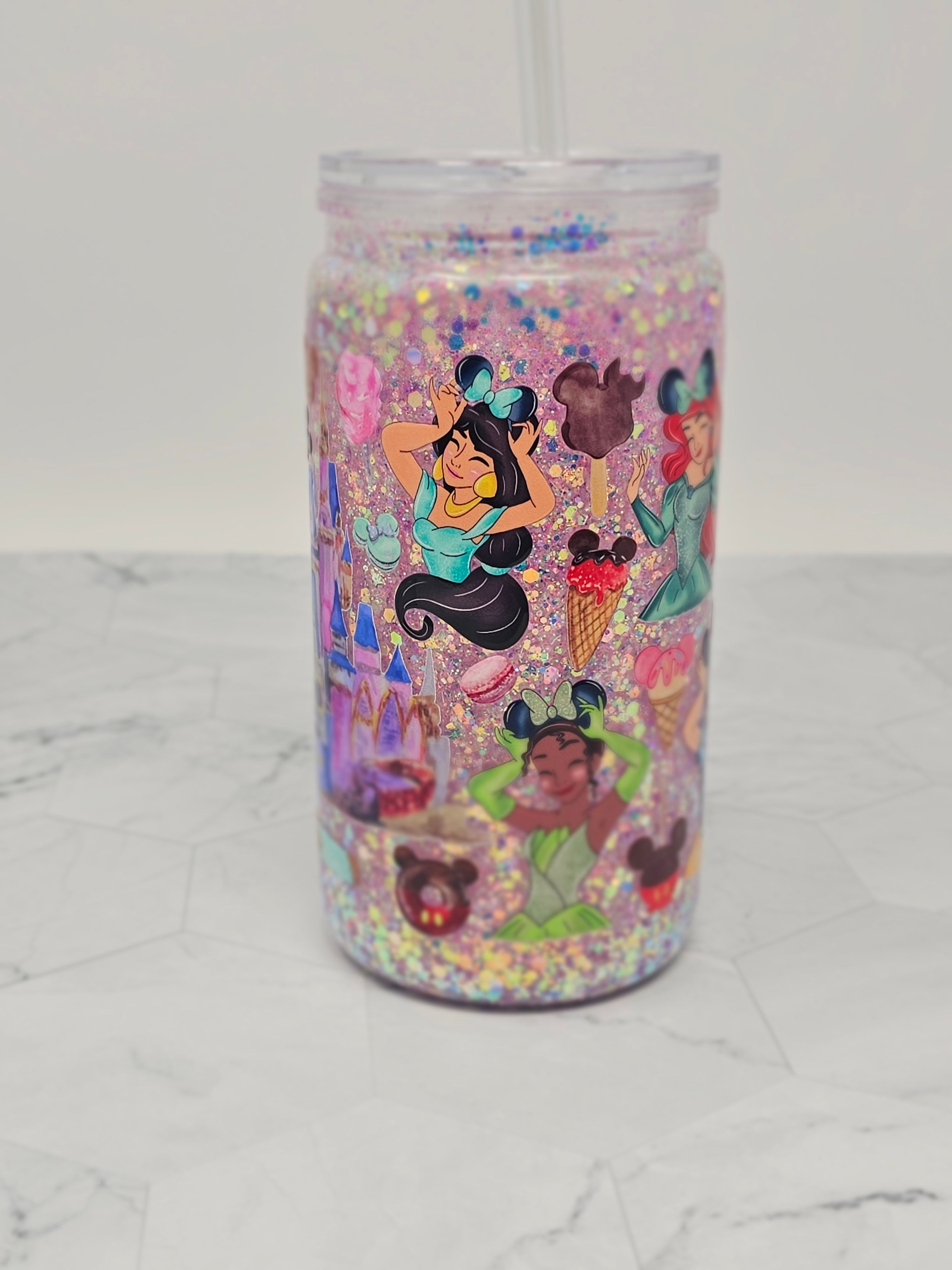 Colorful tumbler with animated character design on a white marble surface. Jasmine, Ariel, Tiana and park snacks