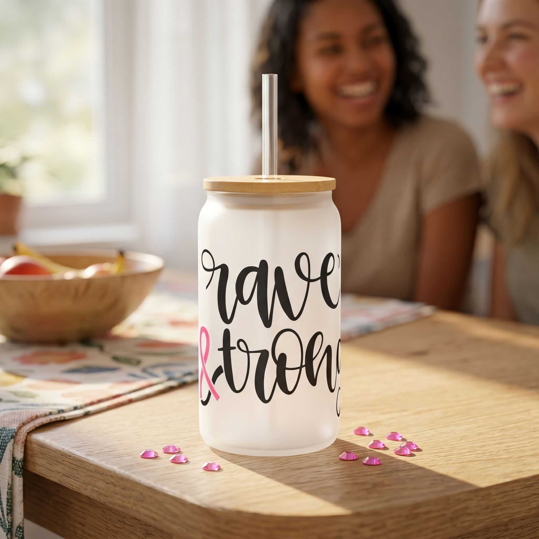 Small transparent glass tumbler with pink ribbon design on wooden table in cozy indoor scene