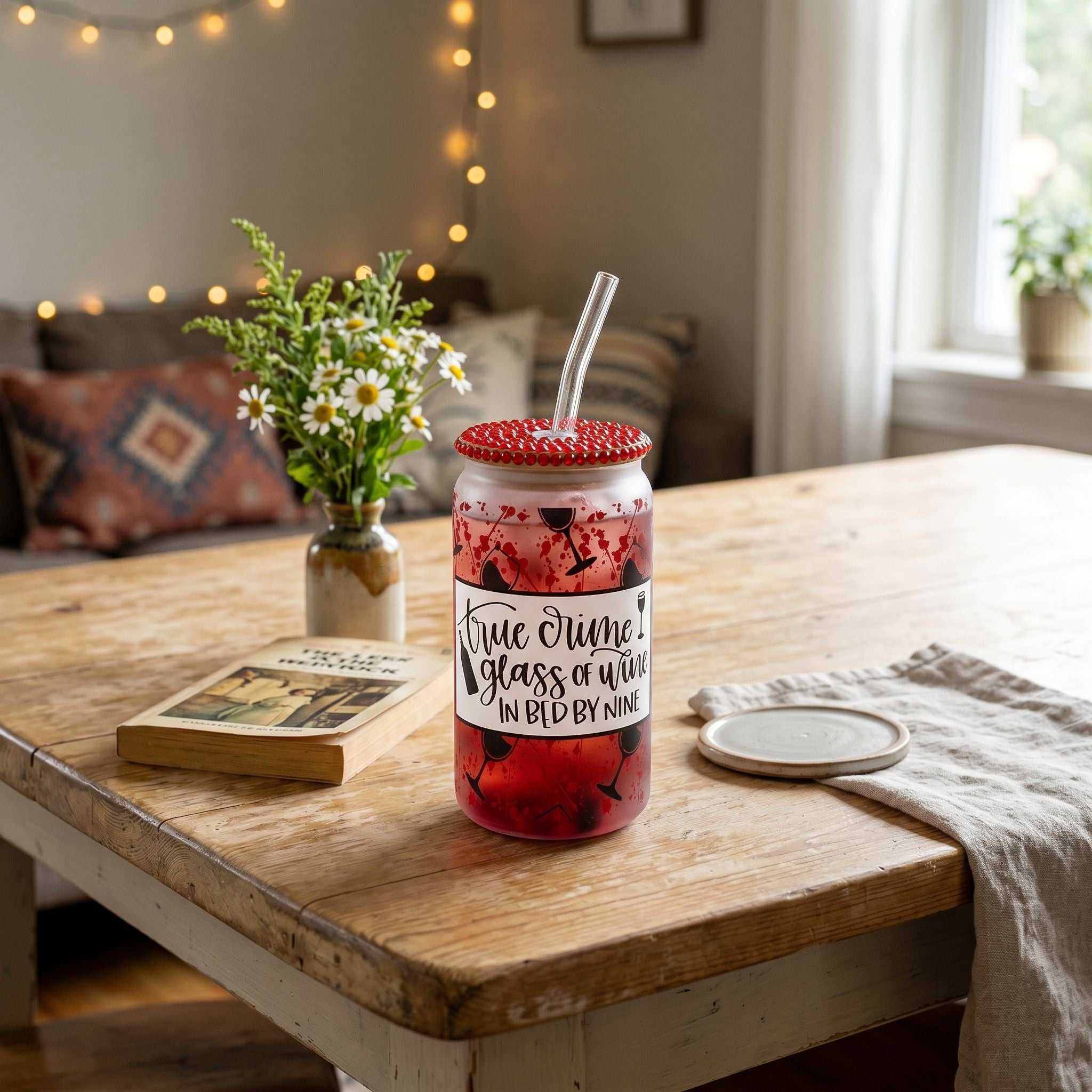 Full view of 16 oz tumbler with beverage on cozy table setting with book and flower for relaxed vibe.