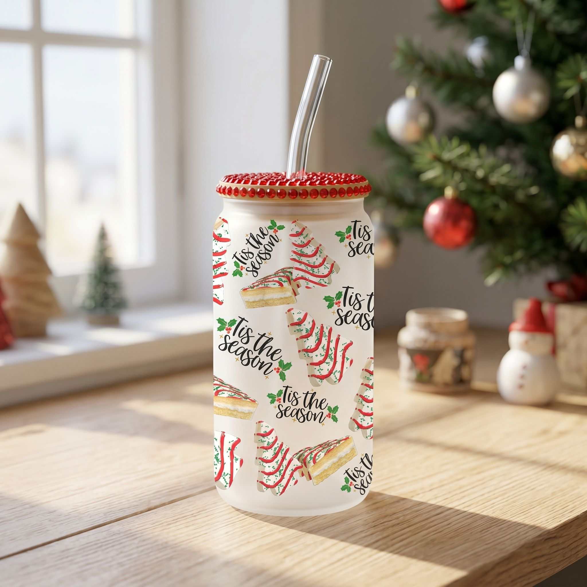 Clear sublimated Christmas-themed 16 oz glass tumbler on natural stone countertop, ideal for holiday beverages and gift-giving.