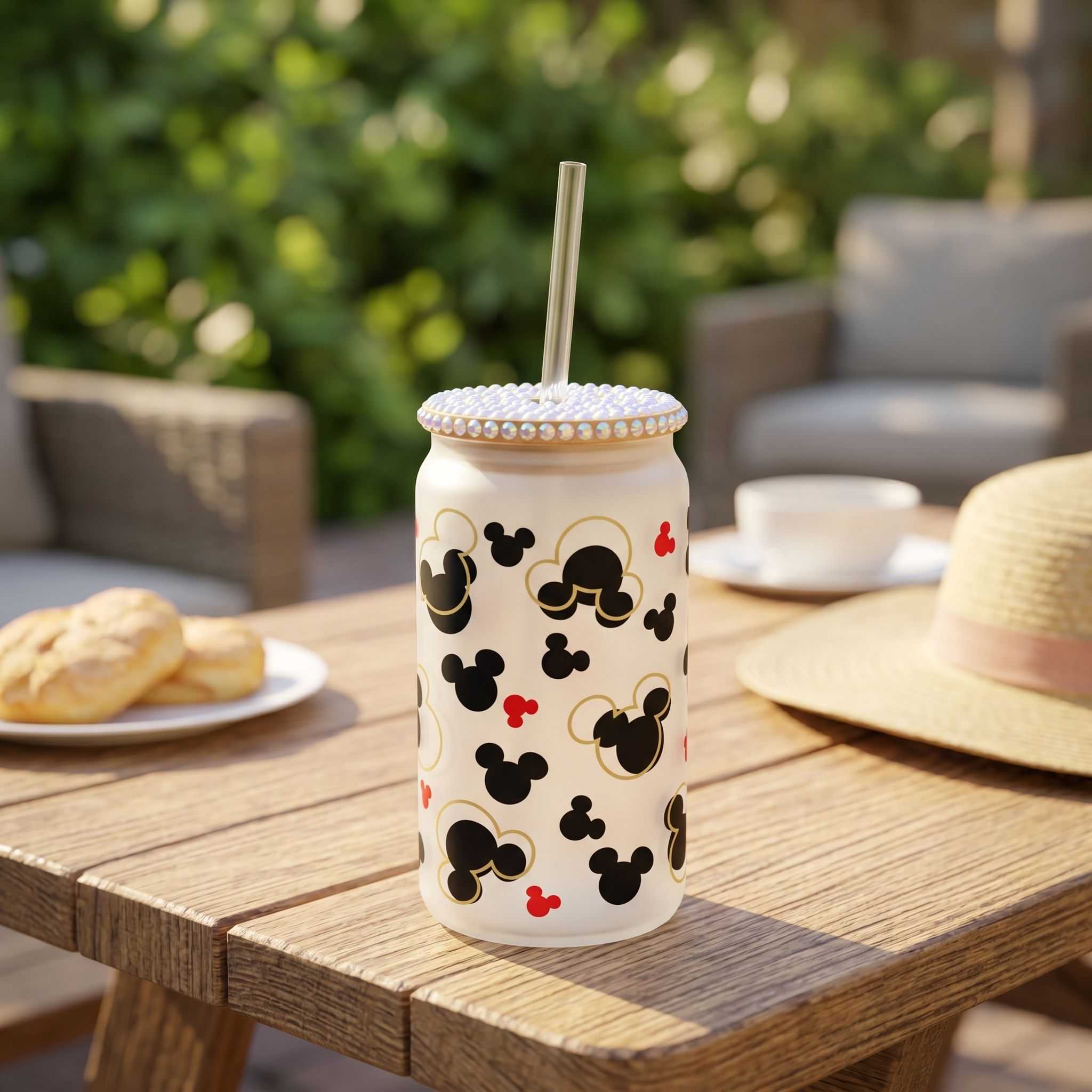 16 oz Mickey Shapes Libby Glass beer can style cup on outdoor picnic table with sunlight, featuring sublimated Mickey design and straw, in a cheerful summer setting.