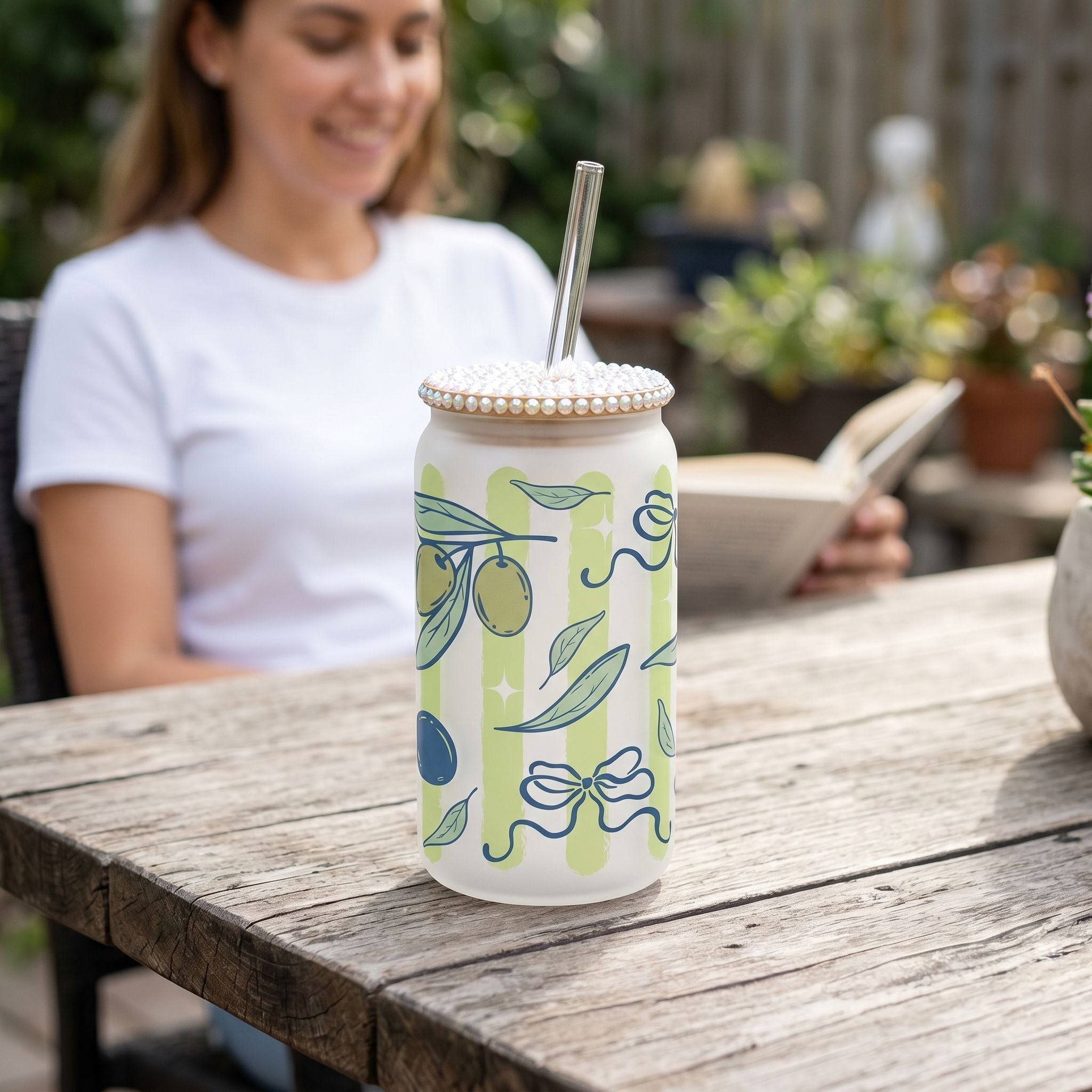 Close-up of a 16oz Libby glass beer can cup with olives and green stripes, highlighting vibrant design and textured glass on rustic wooden table.