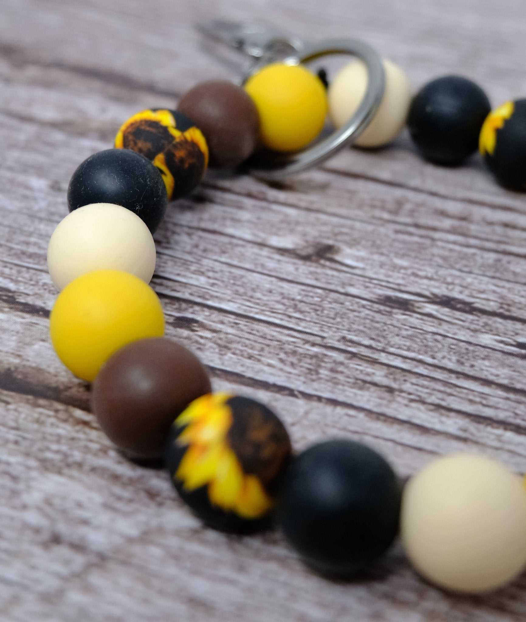 Sunflower black and yellow beaded wristlet keychain with silver lobster clasp on table